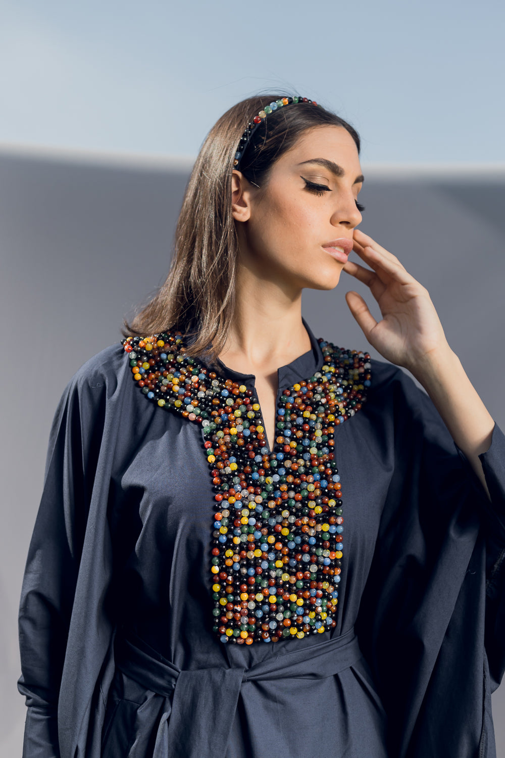 A long sleeve kaftan made of navy blue poplin cotton detailed by a lose fit, light collar, soft belt and easy-going pockets. Embellished by hand embroidered Multicolor Precious Stone beads creating a vibrant energy. Best paired with the Multicolor Precious Stone Headband for a full look.